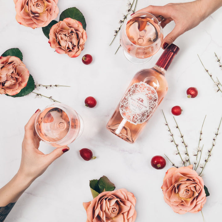Rosé wijnfles en glazen met Italiaanse wijn, omringd door roze rozen op marmeren tafel