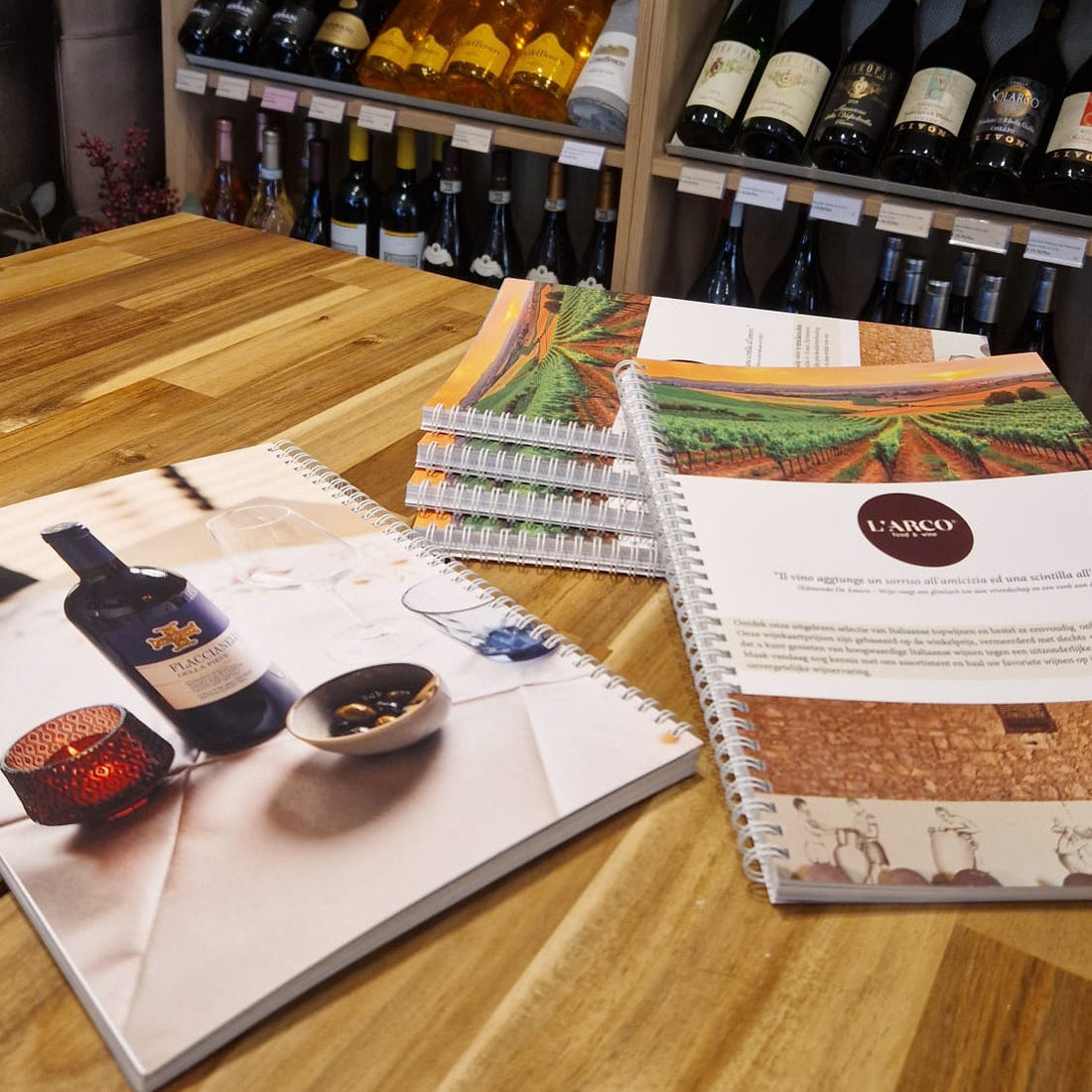 Italiaanse wijnkaarten van L'ARCO op houten tafel, wijnflessen op achtergrond, wijnhandel